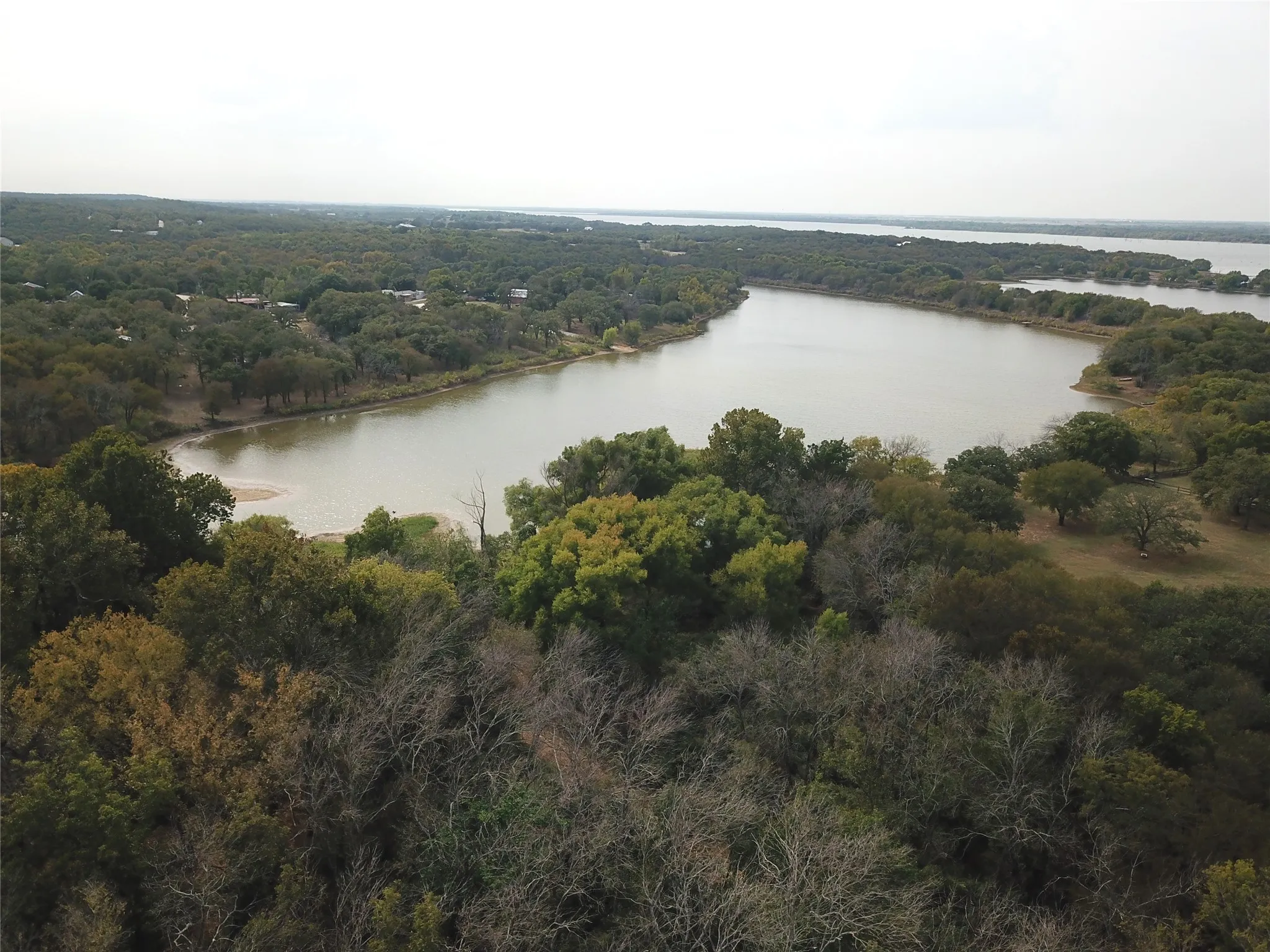 Aerial view of property and surrounding area with a heavily wooded area and a nearby body of water