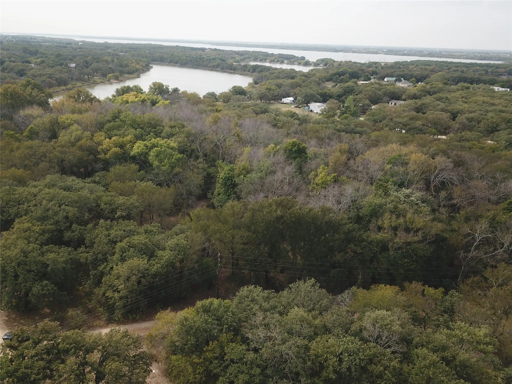 Aerial view of property and surrounding area with a heavily wooded area and a nearby body of water
