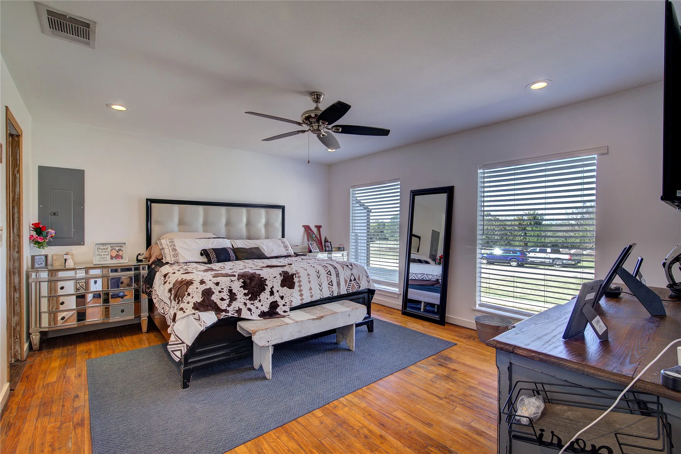Primary bedroom has lots of natural light, vintage hardwood floors, recessed lighting, ceiling fan.