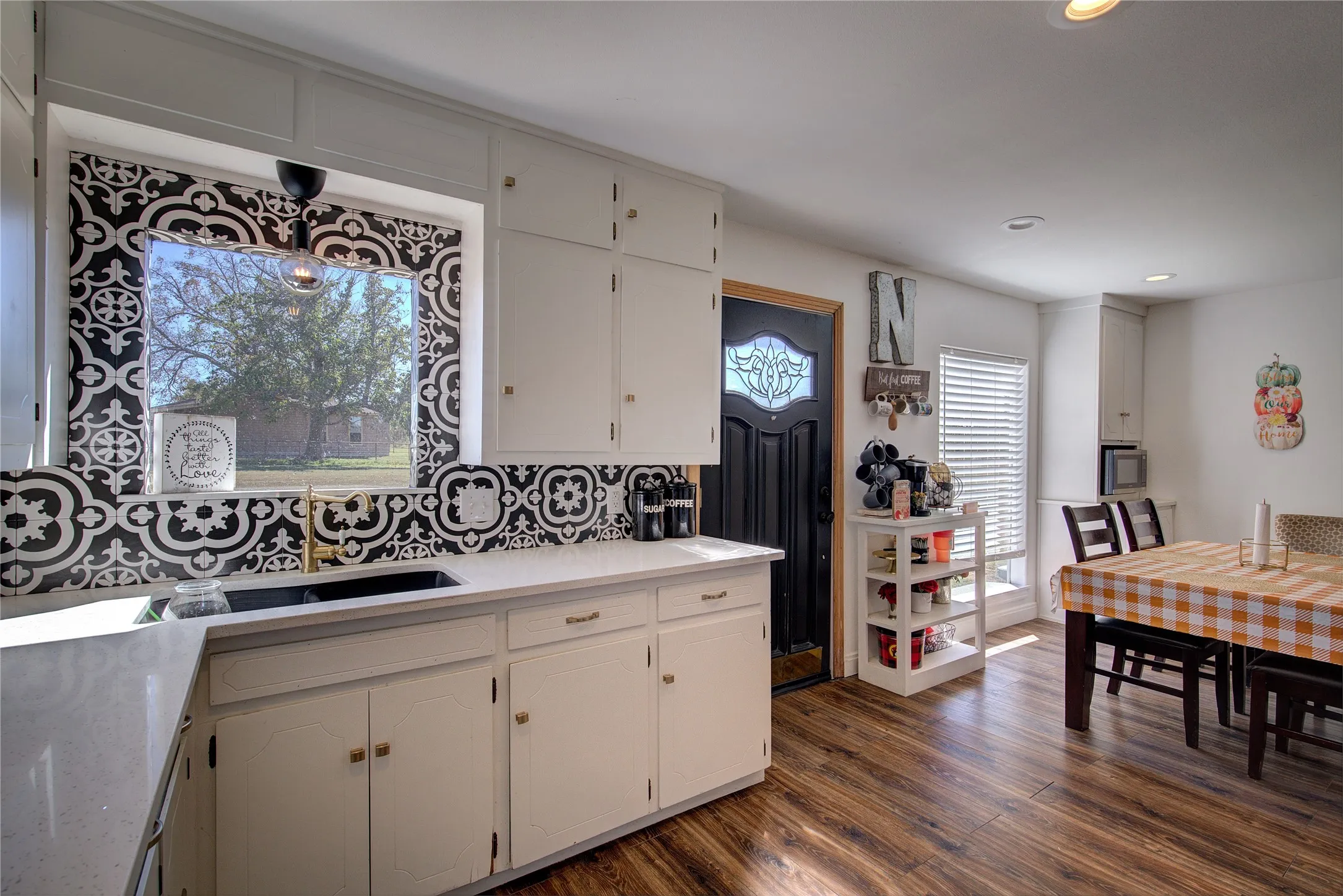 Back wall of kitchen has window, custom tile backsplash and second, divided undermount sink.