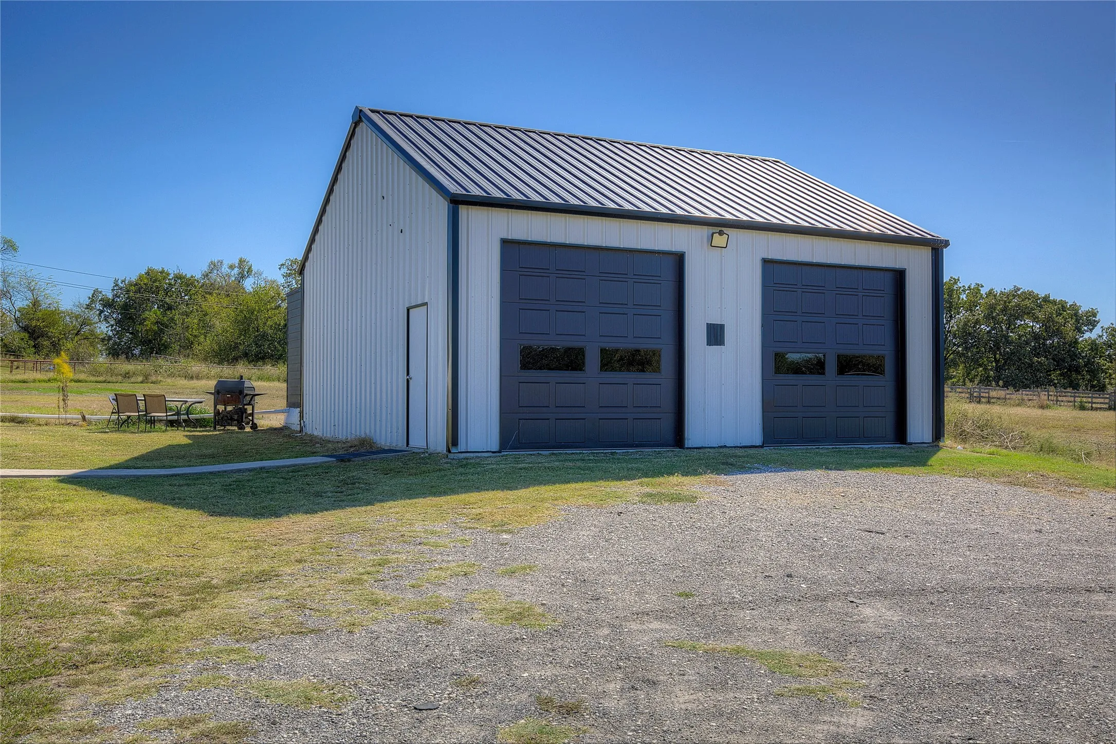 Detached garage has extra-tall roll-up doors, suitable for boat or RV storage.