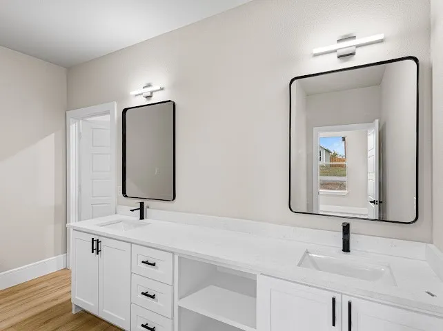 Full bathroom featuring double vanity and light wood finished floors