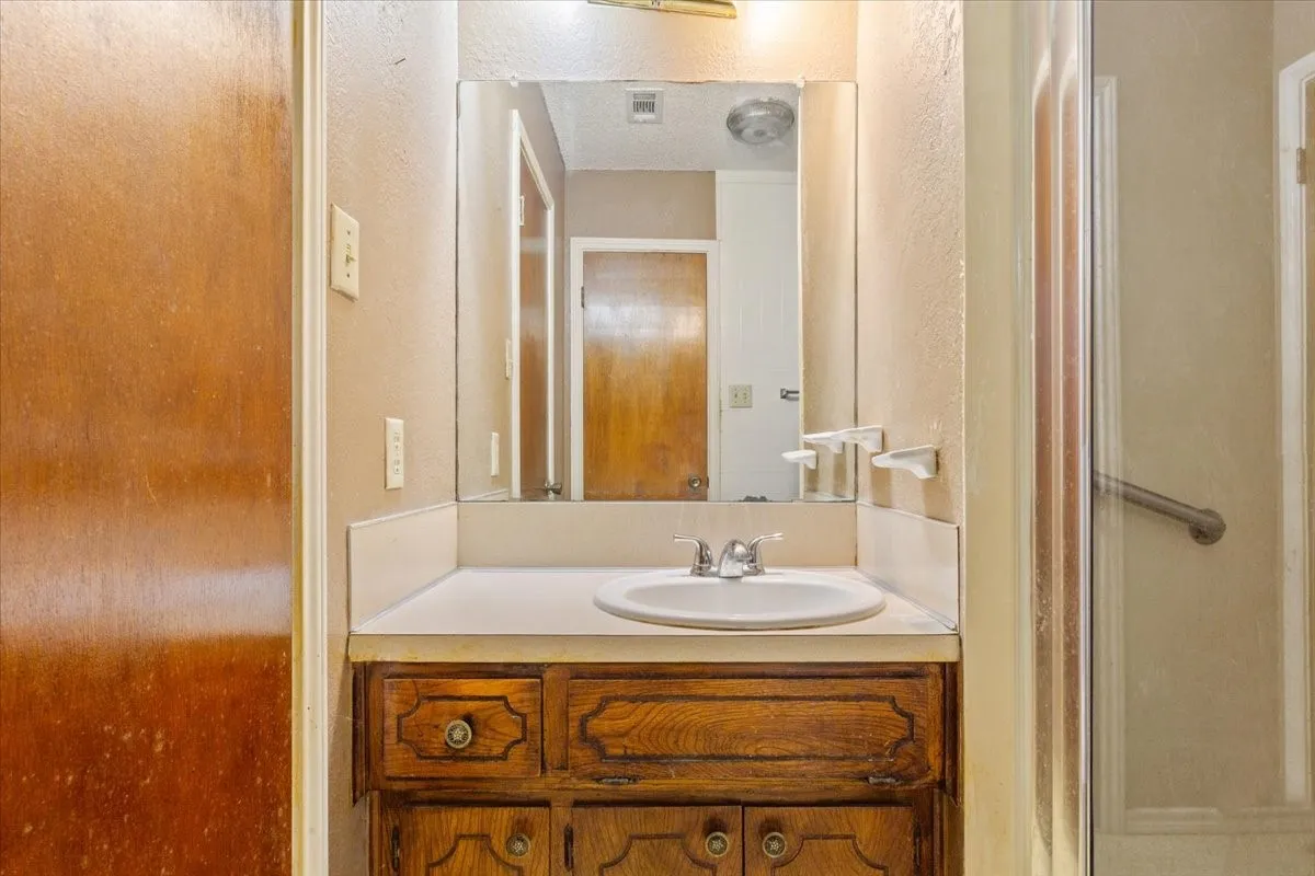 Bathroom featuring vanity, a textured wall, and a shower stall