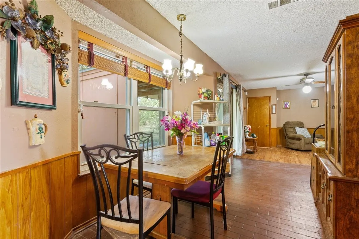 Dining area with wainscoting, a chandelier, wood walls, a textured ceiling, and ceiling fan