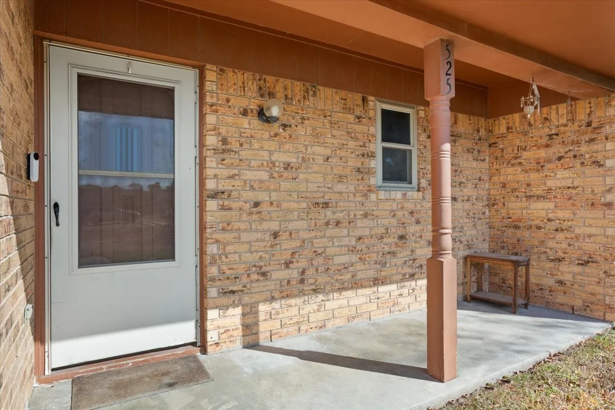 Doorway to property with brick siding and a porch