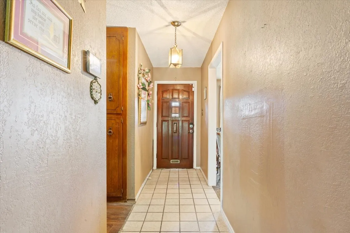 Corridor featuring a textured wall and light tile patterned floors
