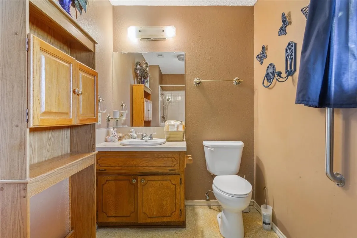Full bath with vanity, a textured wall, and a​​‌​​​​‌​​‌‌​‌‌​​​‌‌​‌​‌​‌​​​‌​​ shower