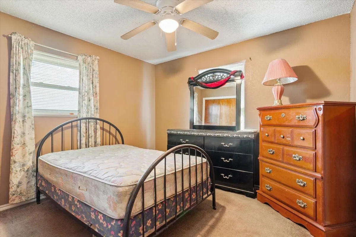 Carpeted bedroom with a textured ceiling and a ceiling fan