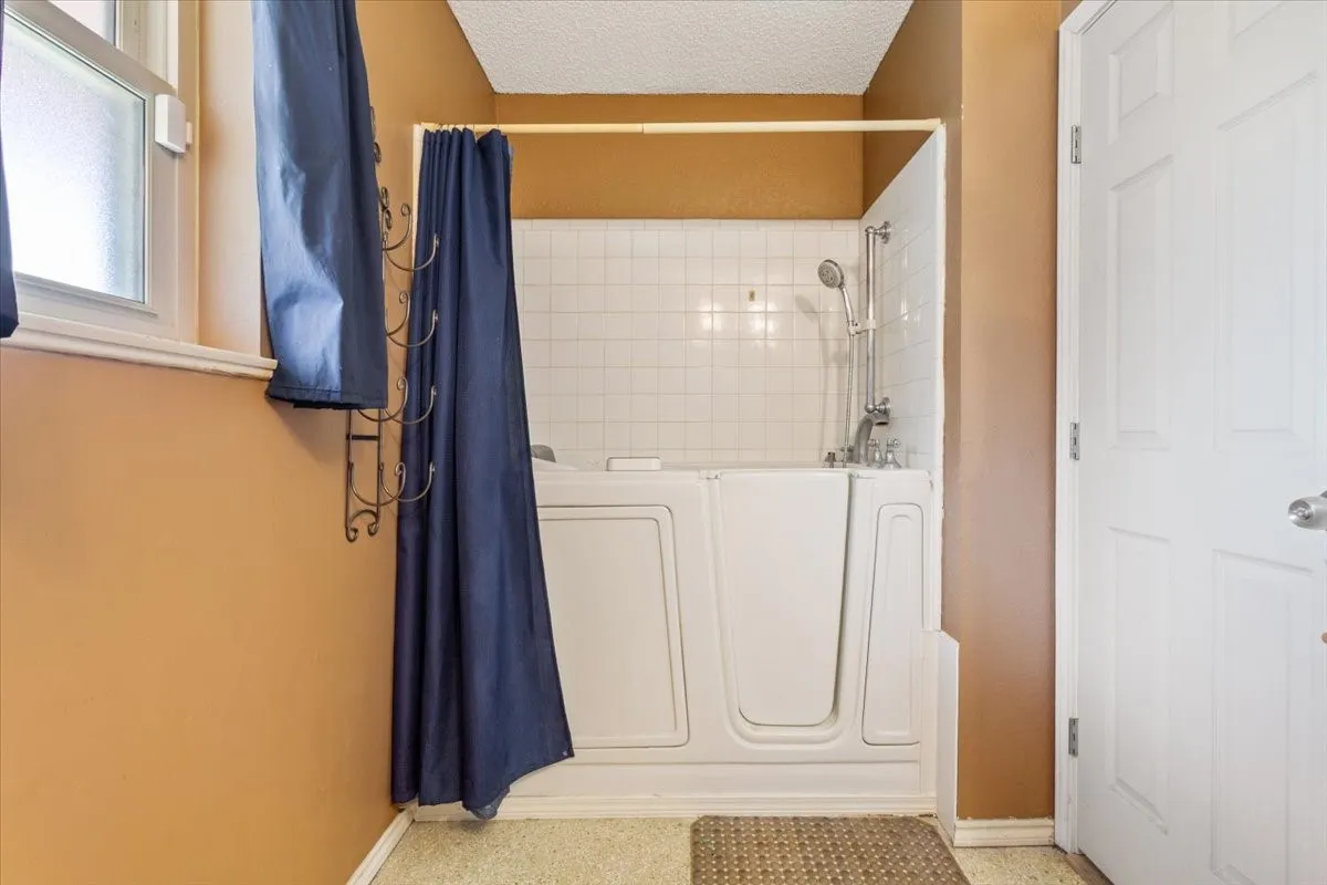 Full bath featuring shower / bath combo and a textured ceiling