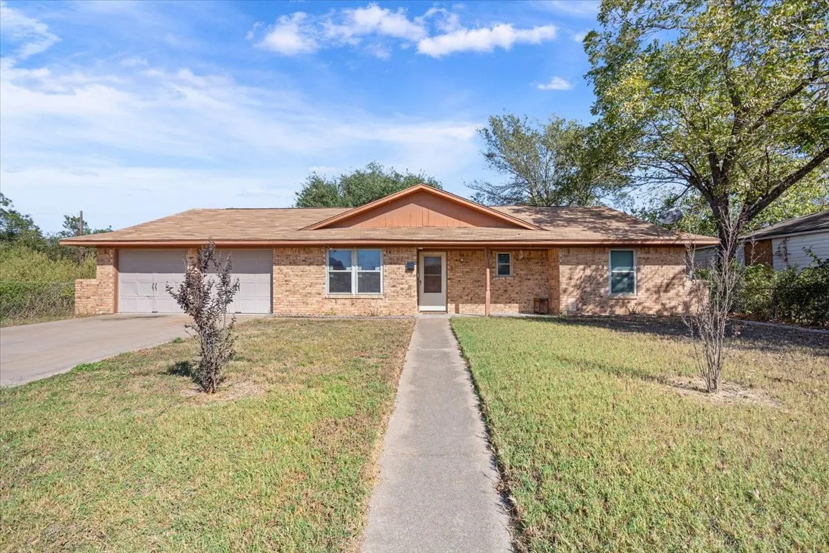 Ranch-style house featuring concrete driveway, a front lawn, brick siding, and a garage