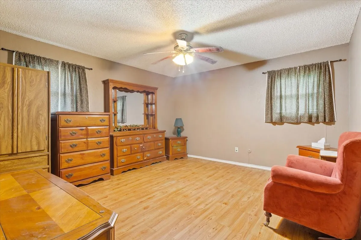 Sitting room featuring a textured ceiling, light wood-style flooring, and ceiling fan