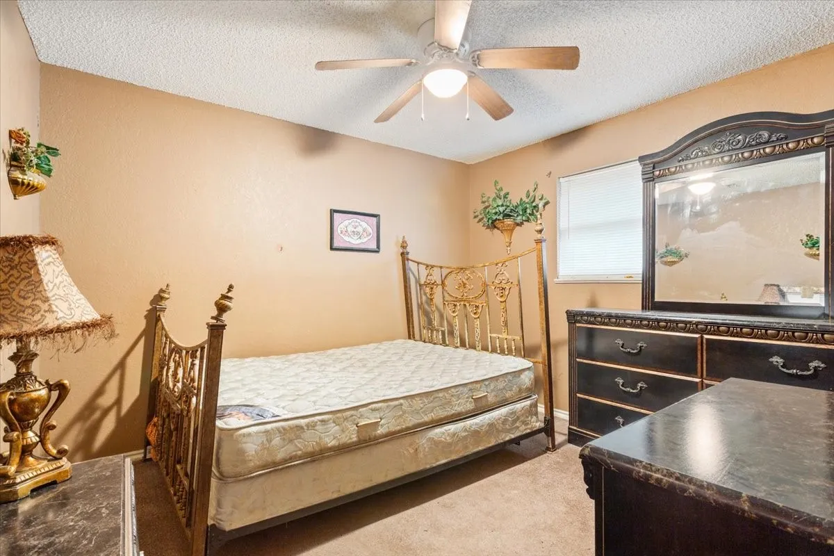 Carpeted bedroom with a textured ceiling and ceiling fan