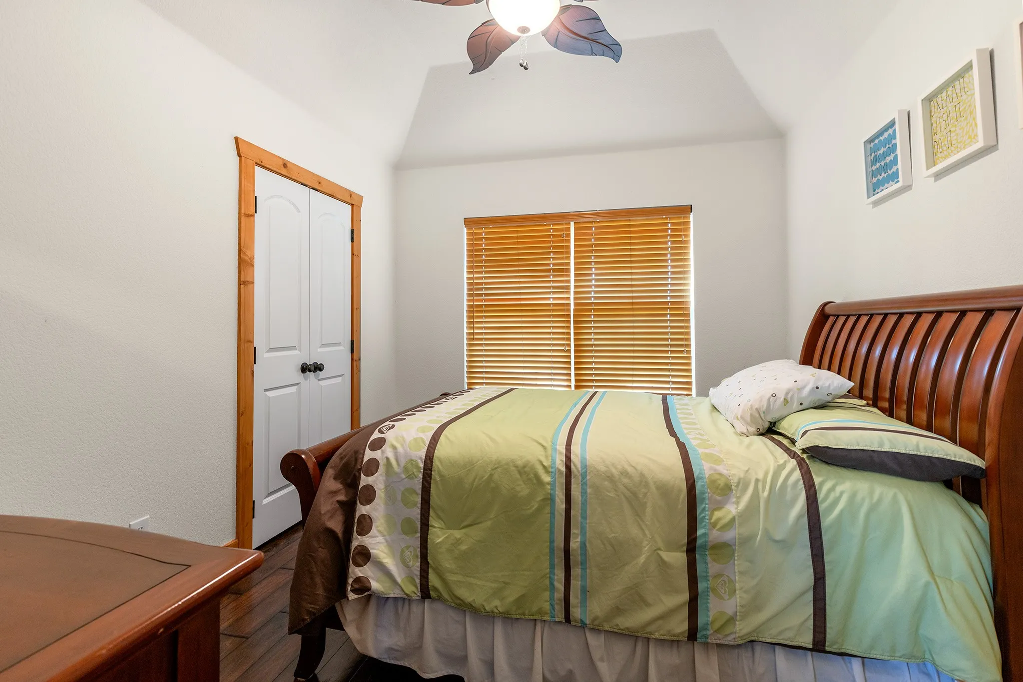 Bedroom with a ceiling fan, a closet, wood finished floors, and vaulted ceiling