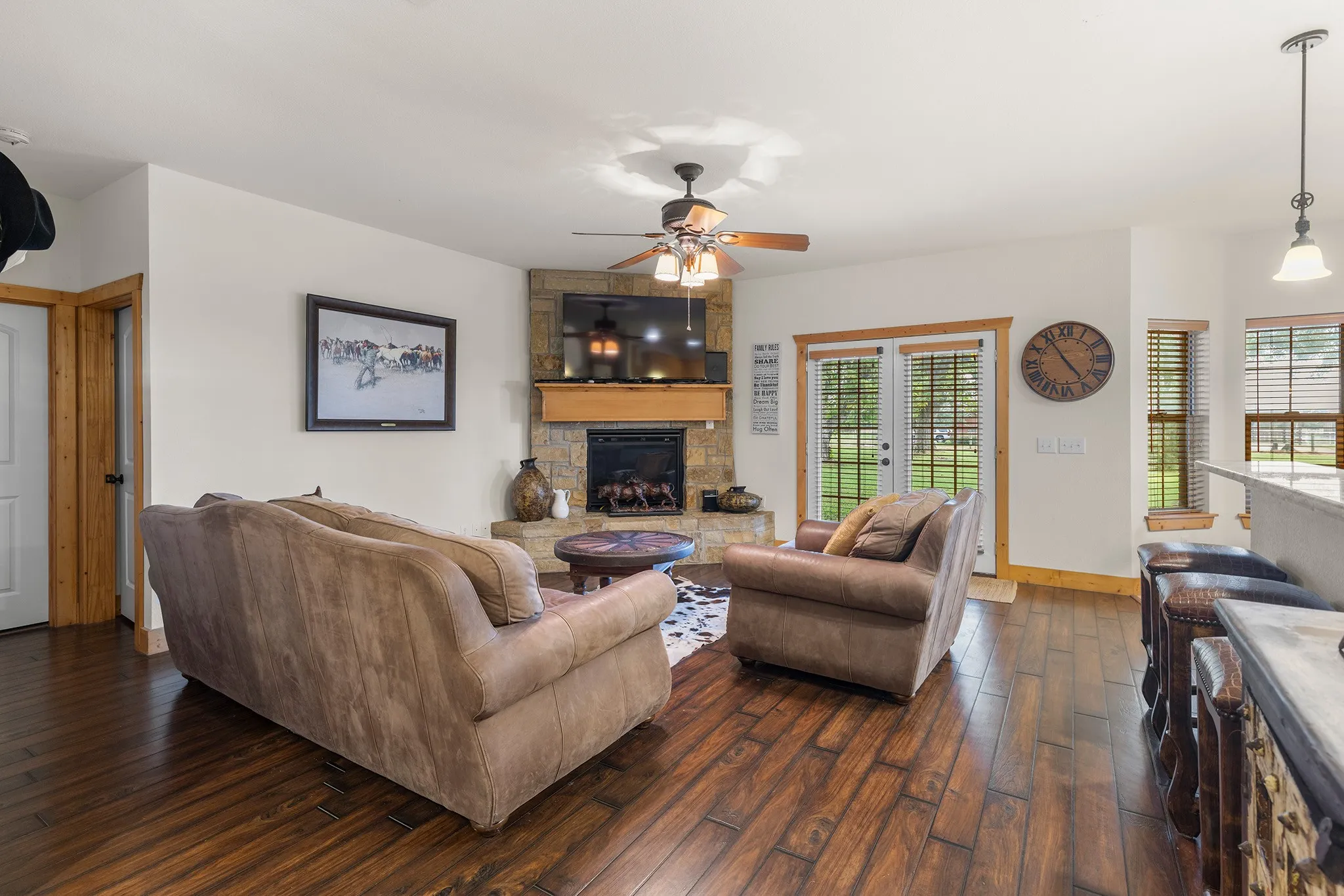 Living area with dark wood-style flooring, a fireplace, and a ceiling fan