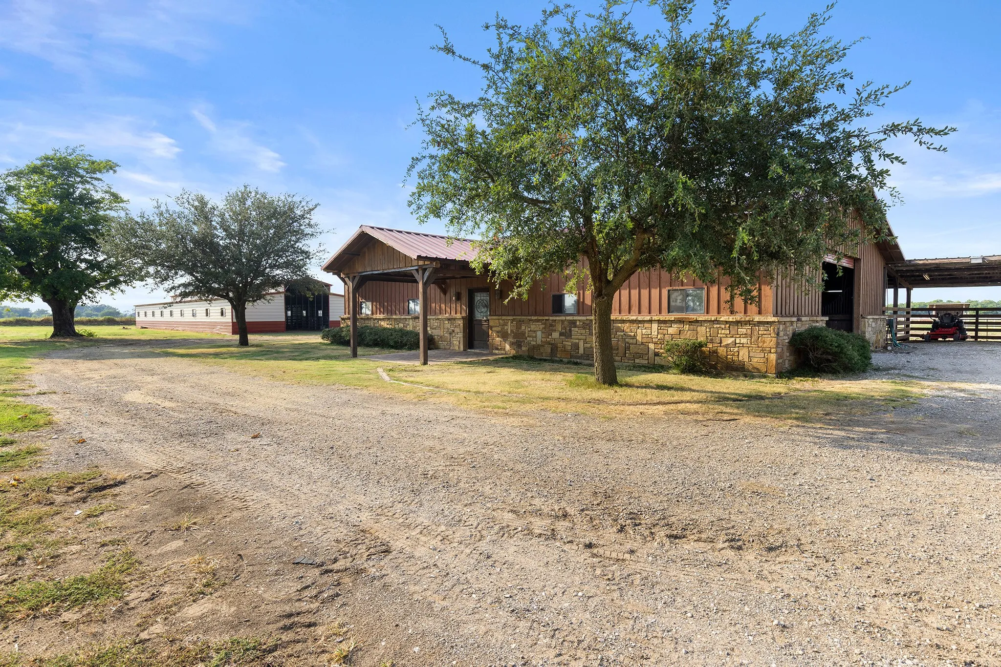 View of front of property featuring stone siding, board and batten siding, and dirt driveway