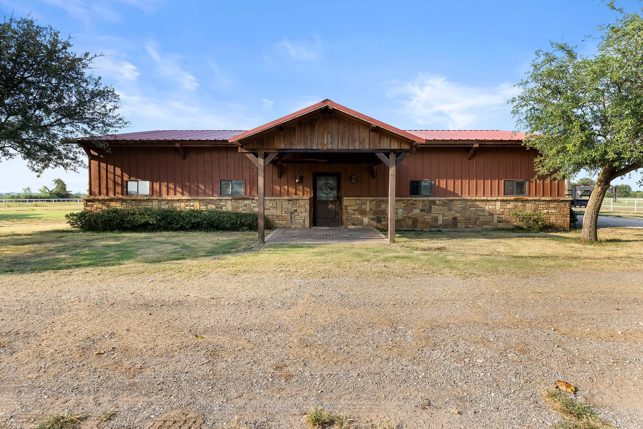 Chalet / cabin with stone siding, covered porch, a metal roof, and board and batten siding