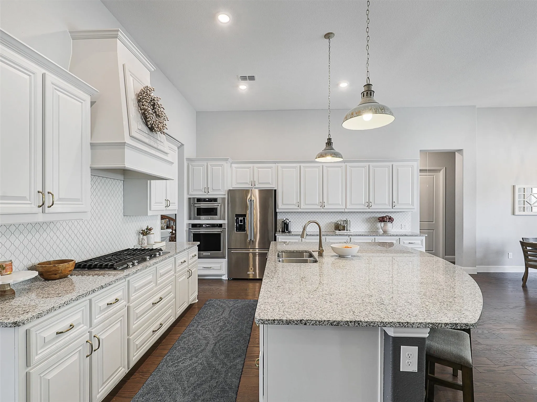 Kitchen featuring tasteful backsplash, light stone counters, white cabinets, decorative light fixtures, and recessed lighting