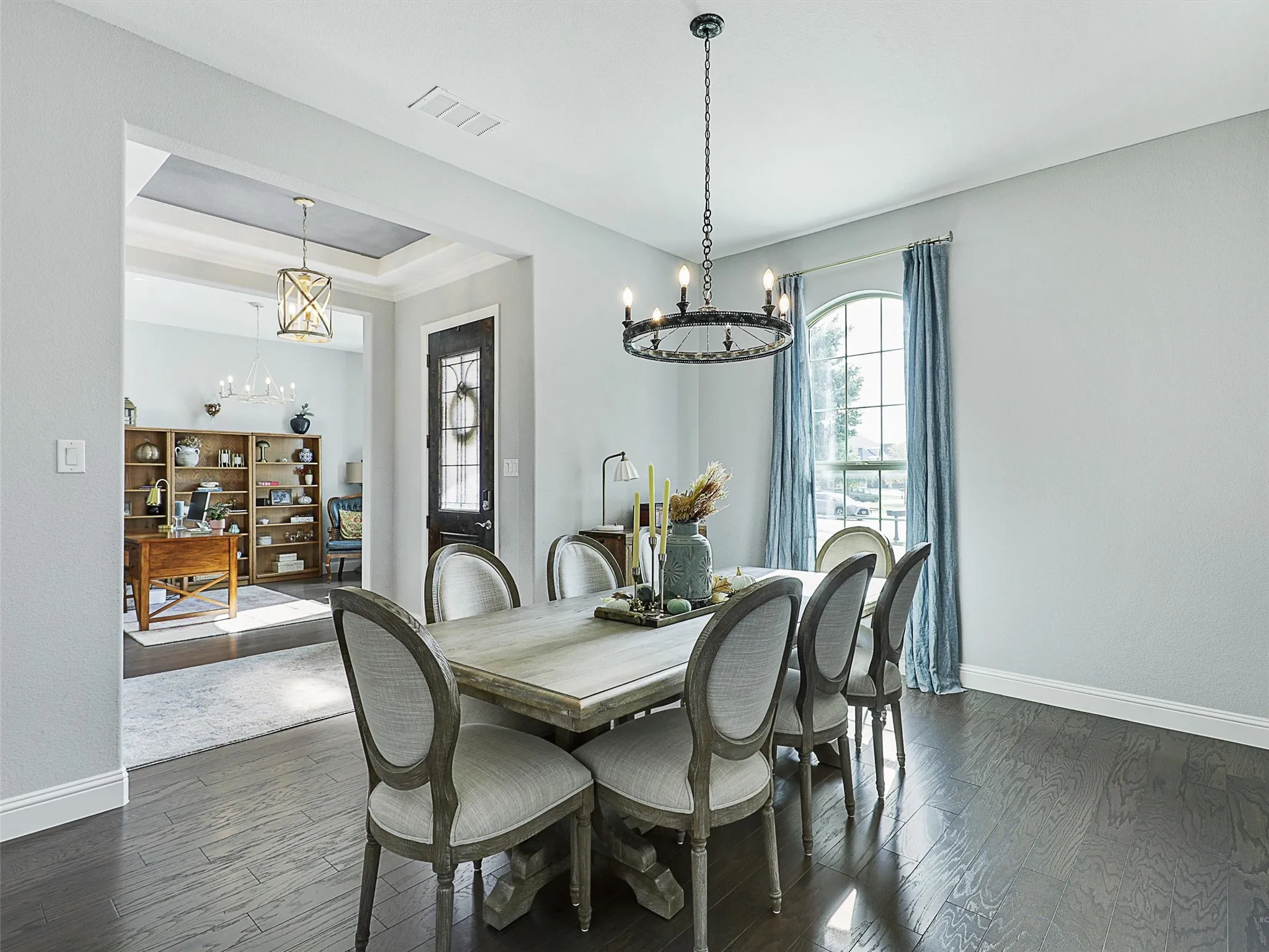 Dining area featuring a chandelier, dark wood-style flooring, and a raised ceiling
