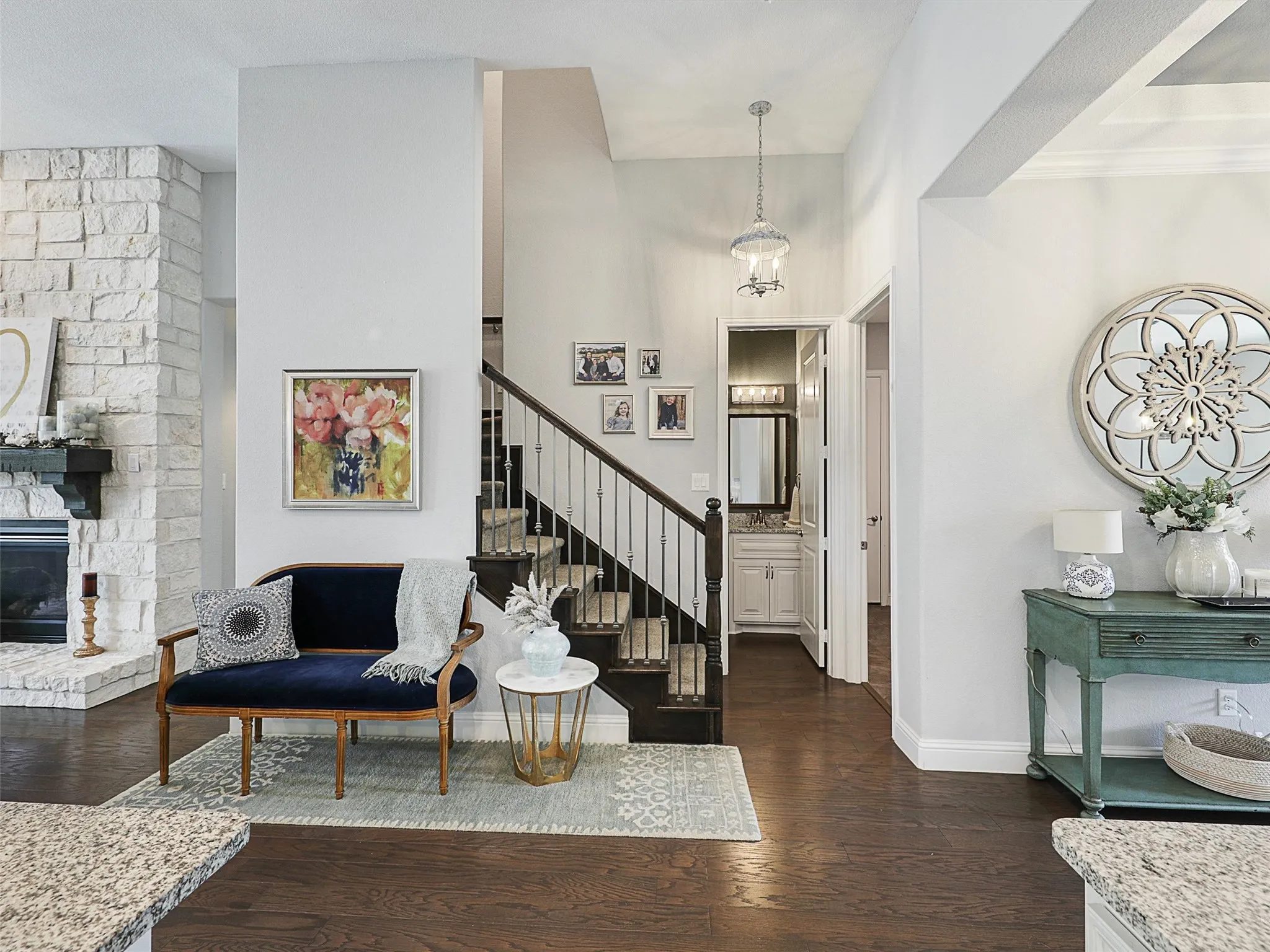 Foyer entrance with dark wood finished floors, a stone fireplace, and stairway