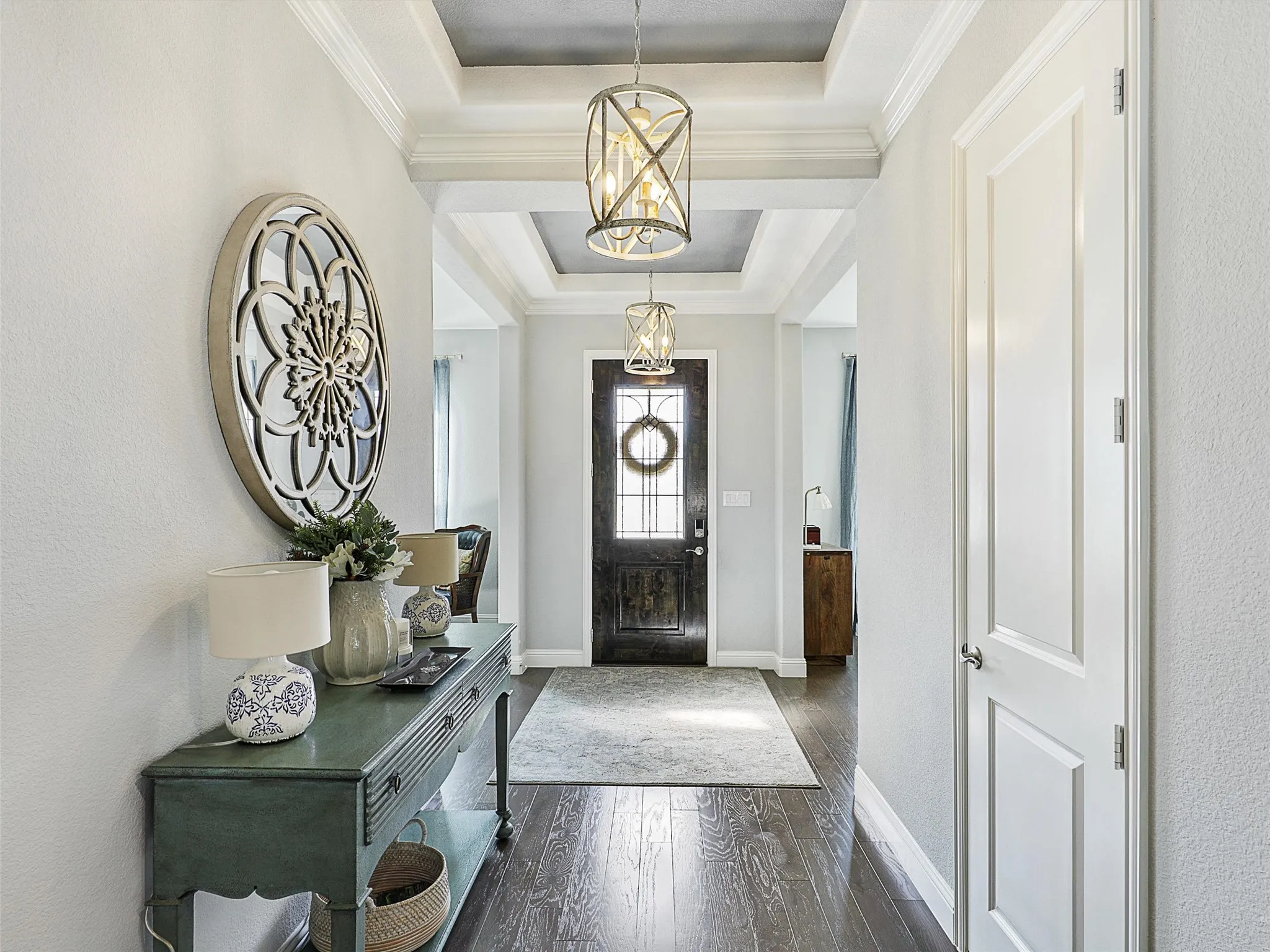 Entrance foyer featuring dark wood-type flooring, a tray ceiling, a chandelier, and ornamental molding