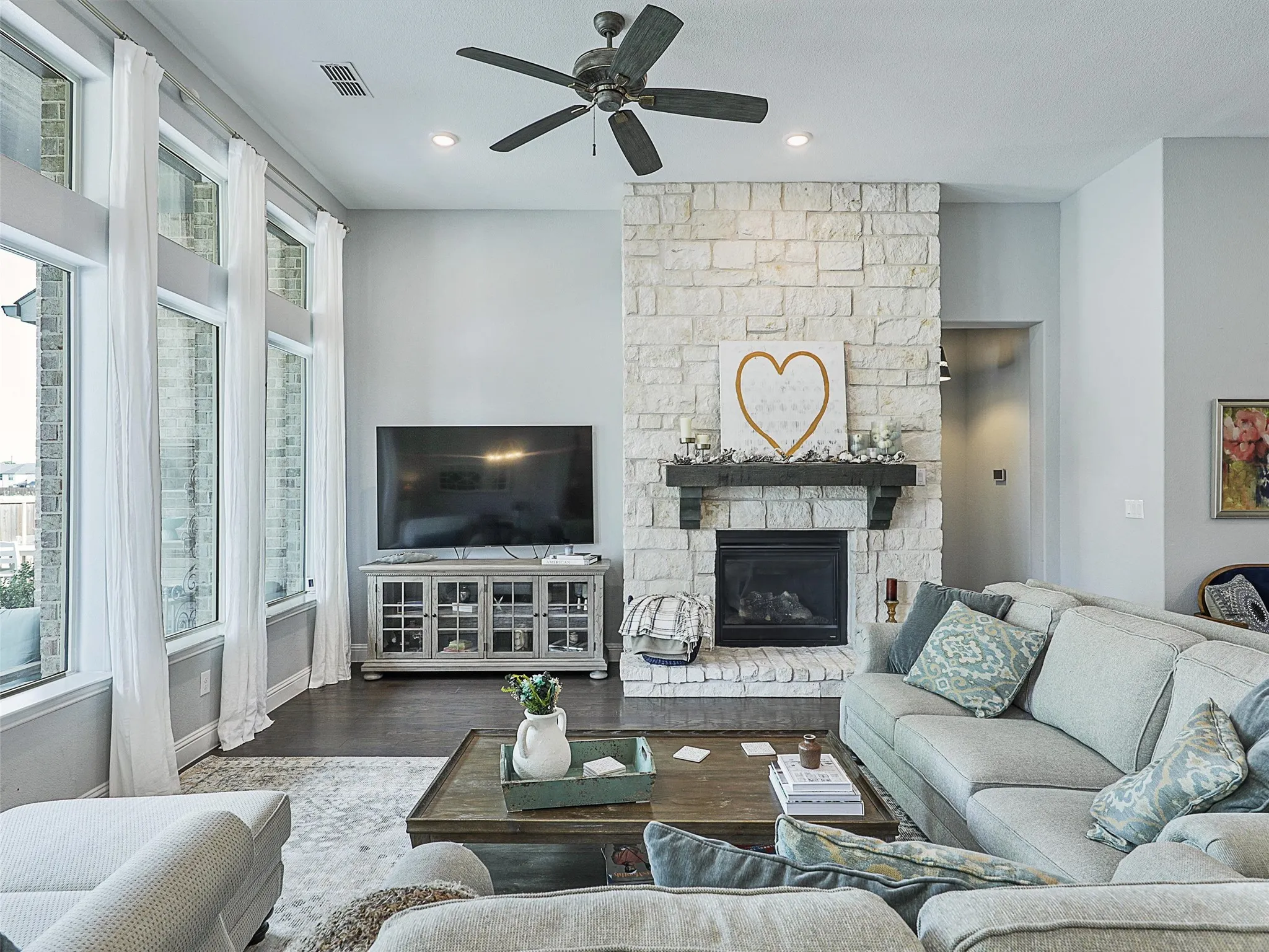 Living room featuring wood finished floors, a fireplace, a ceiling fan, and recessed lighting