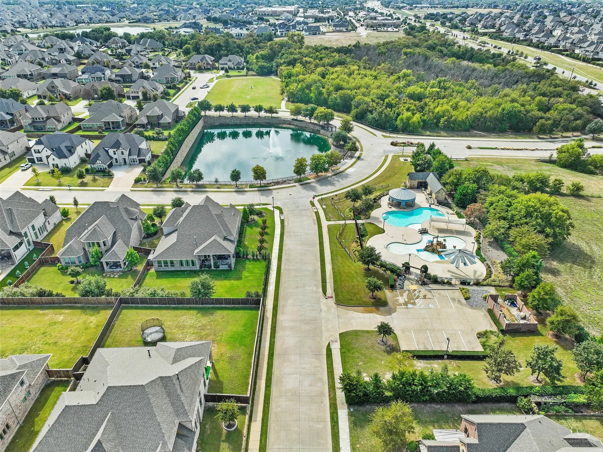 Aerial perspective of suburban area with a large body of water and a pool area