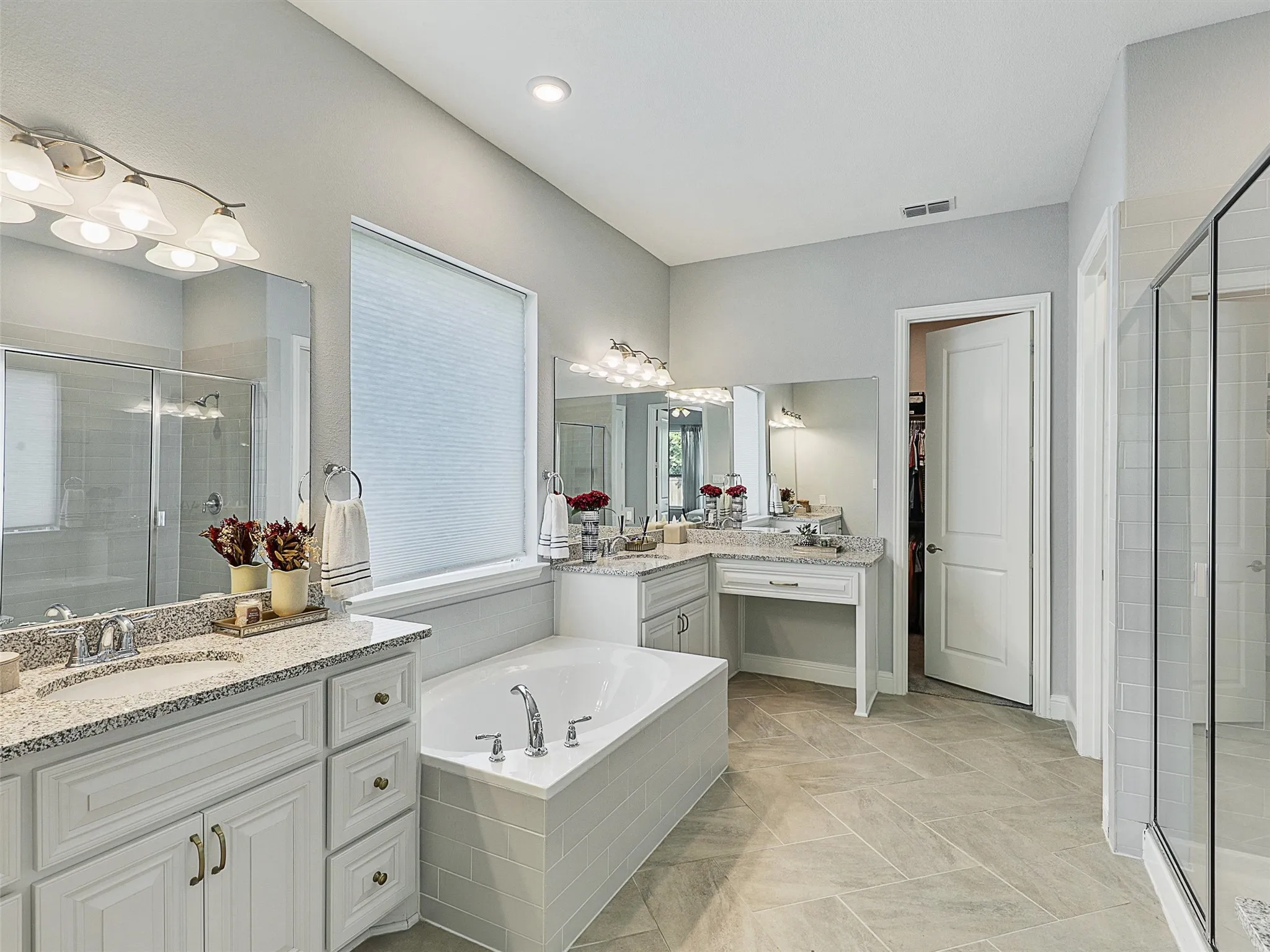 Bathroom with a stall shower, two vanities, a garden tub, and a spacious closet