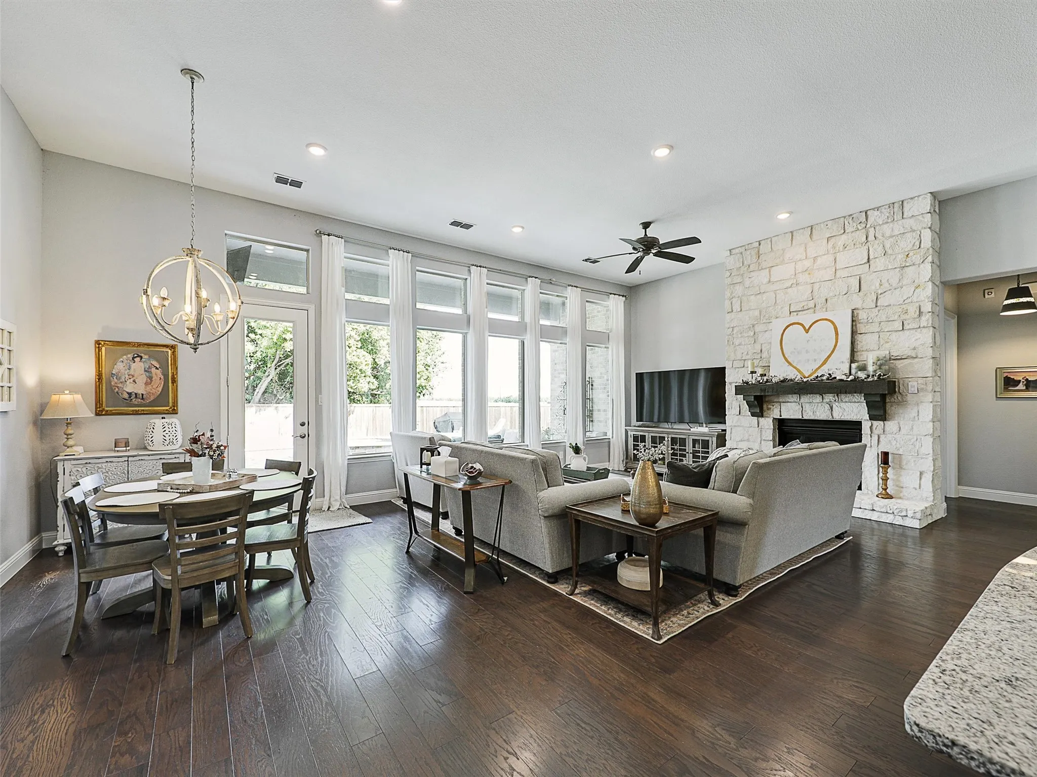 Living room featuring dark wood-style floors, a fireplace, a chandelier, recessed lighting, and a ceiling fan