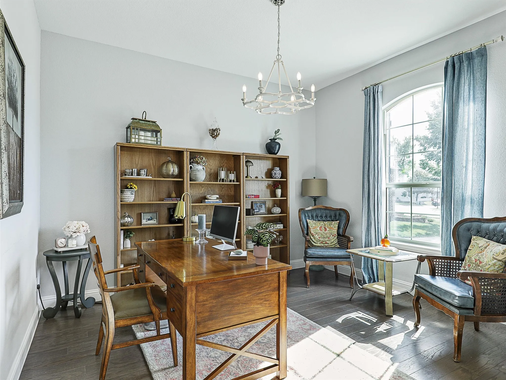 Home office with dark wood-style floors and a chandelier