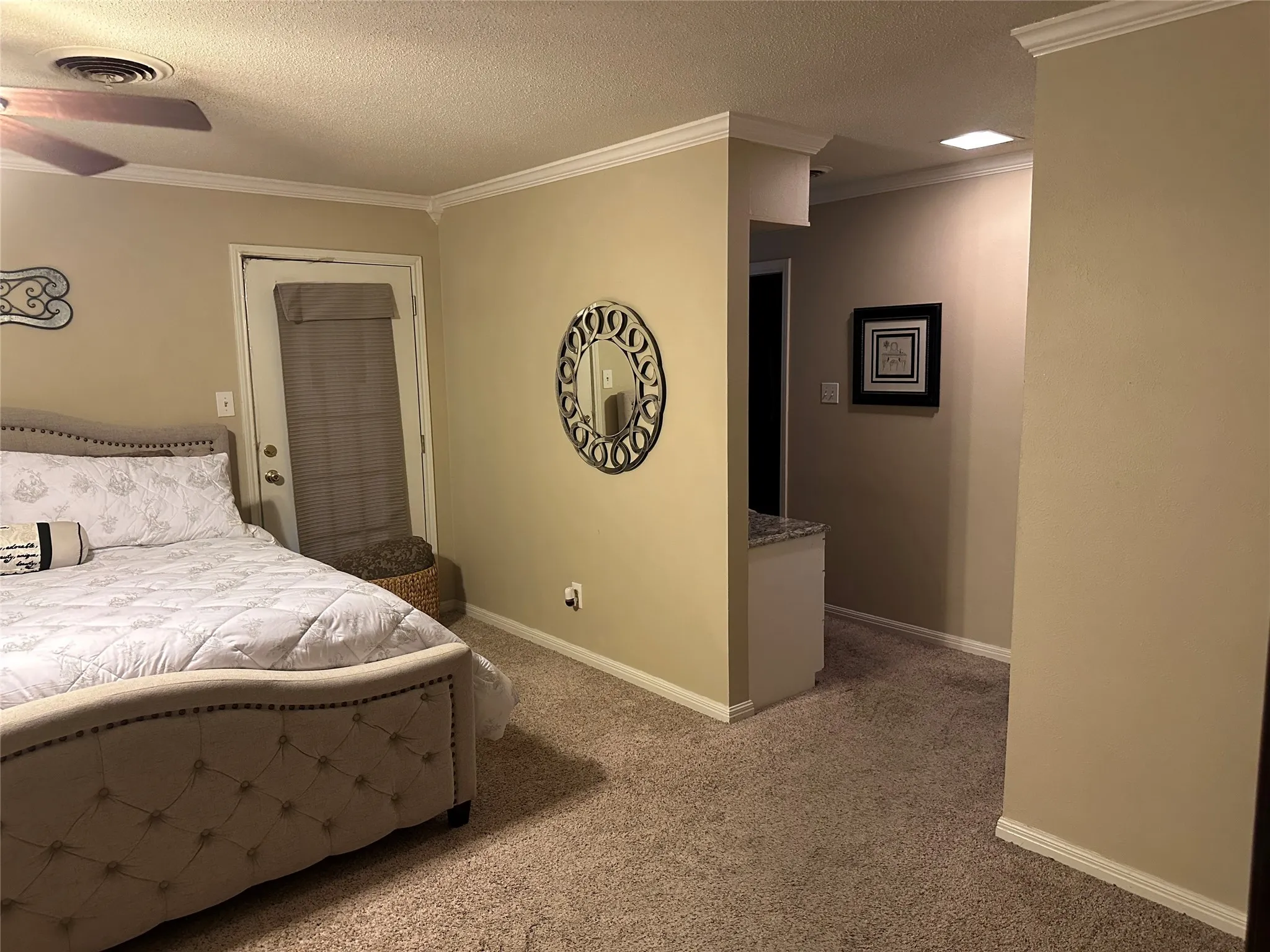 Bedroom with a textured ceiling, light carpet, ornamental molding, and ceiling fan