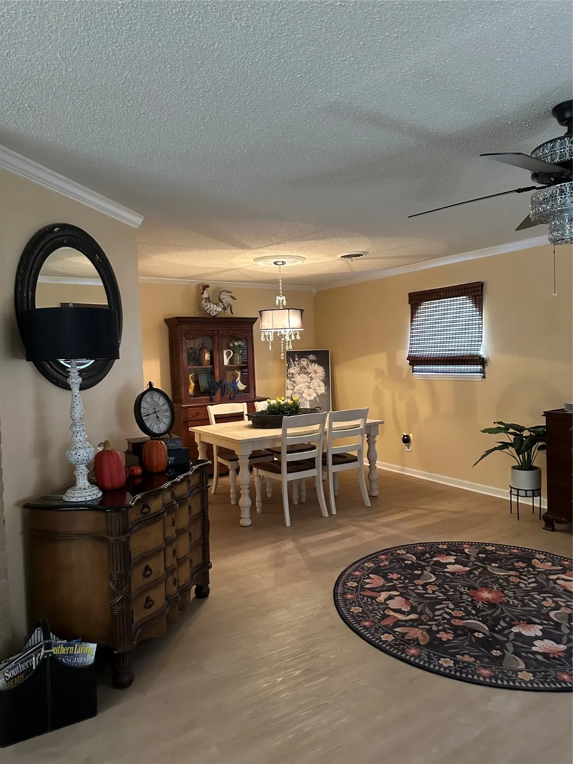Dining space featuring a textured ceiling, ornamental molding, light wood-type flooring, a chandelier, and a ceiling fan