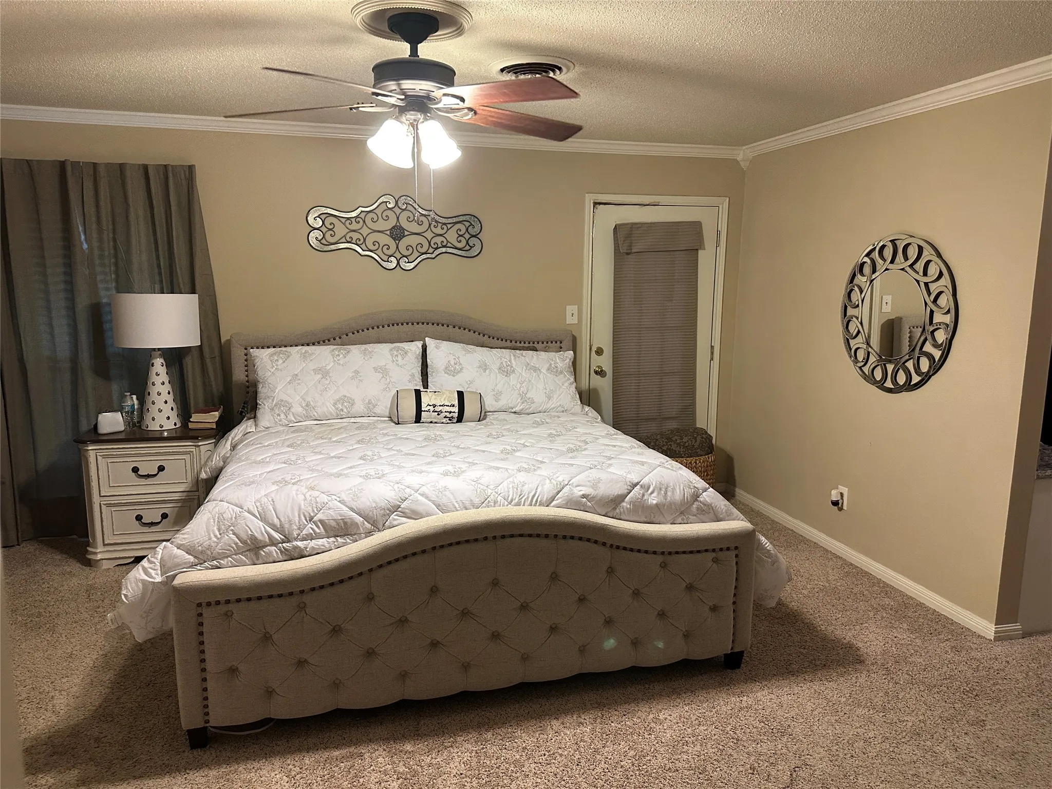 Bedroom featuring a textured ceiling, light carpet, ornamental molding, and ceiling fan