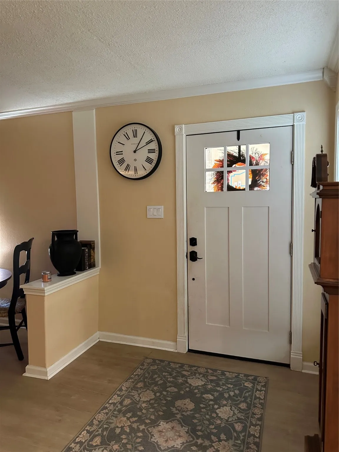 Foyer entrance with a textured ceiling, wood finished floors, and crown molding