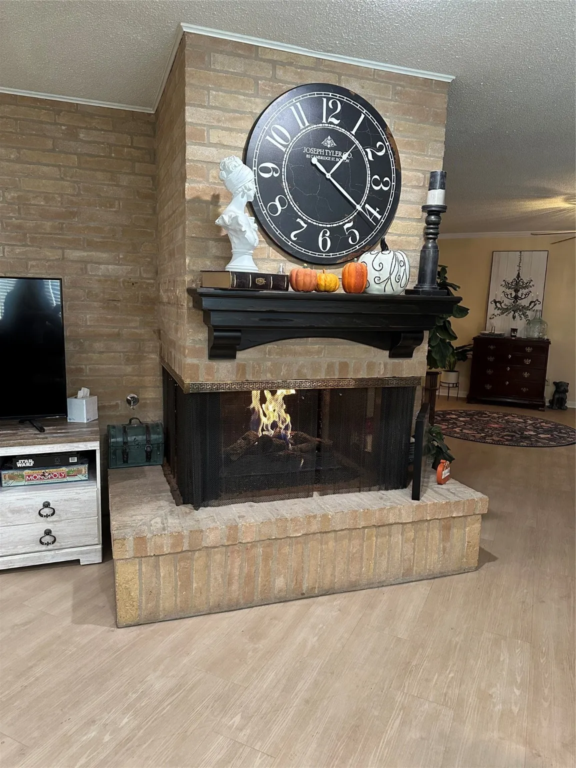 Detailed view of a textured ceiling, a fireplace, wood finished floors, and crown molding