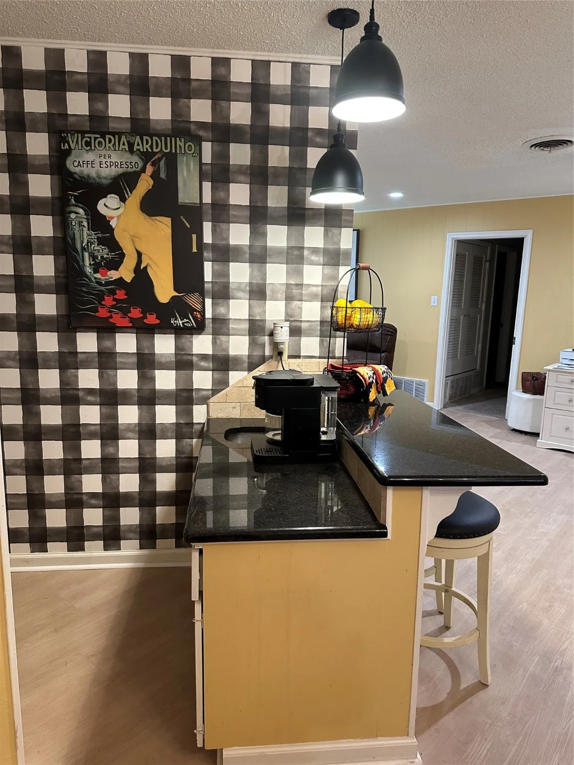 Kitchen featuring a kitchen breakfast bar, pendant lighting, a textured ceiling, dark stone counters, and a peninsula