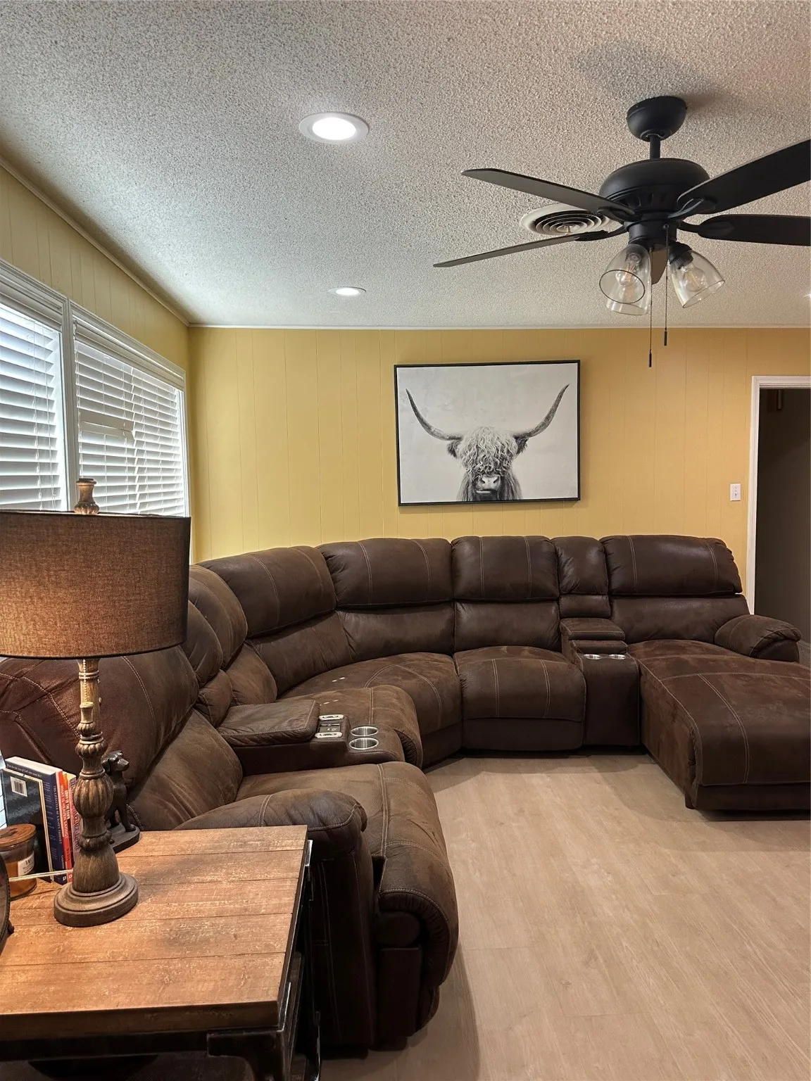 Living area with a textured ceiling, wood finished floors, ceiling fan, and wooden walls