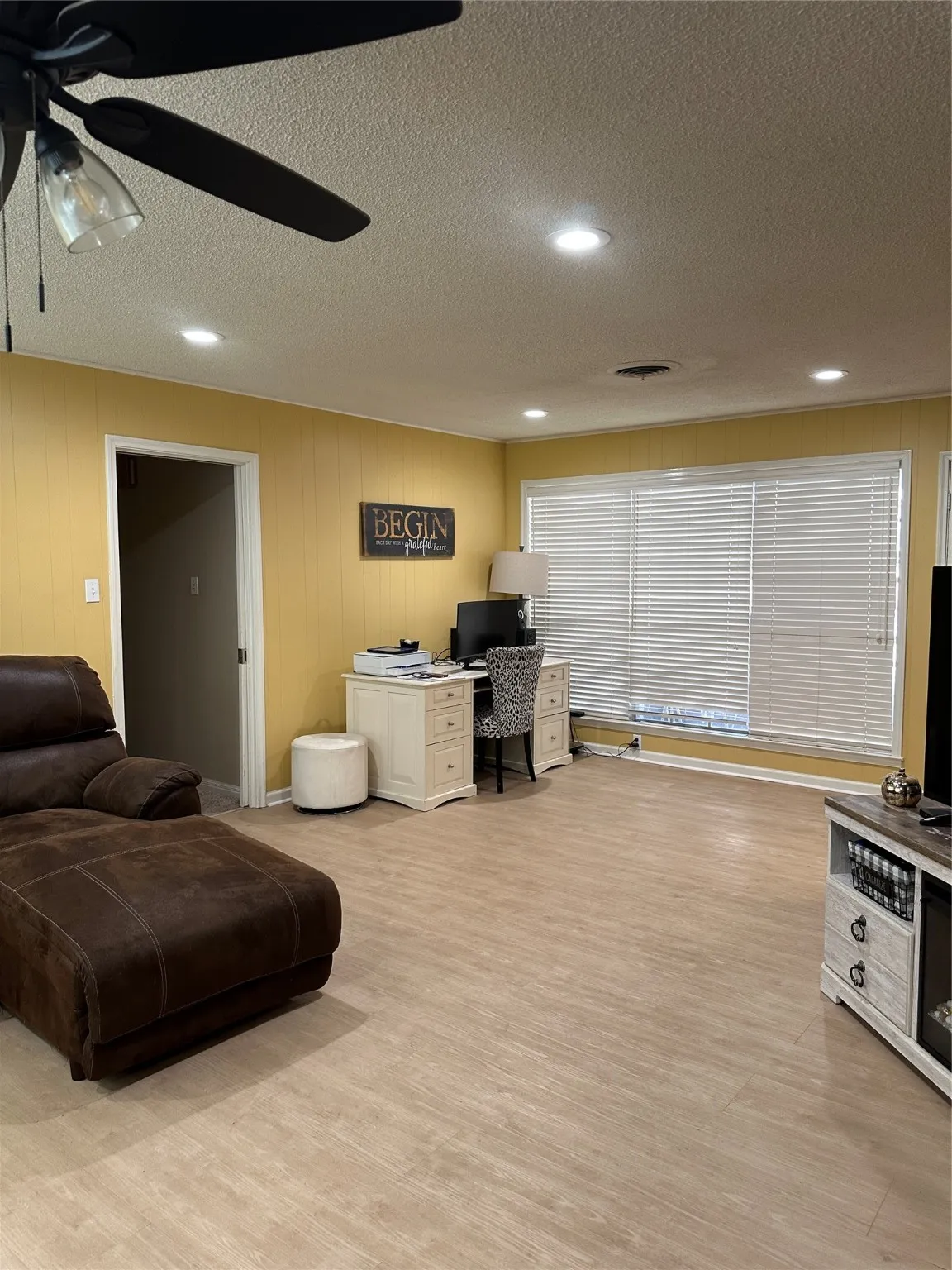 Office space featuring light wood-style flooring, a textured ceiling, recessed lighting, a ceiling fan, and wood walls