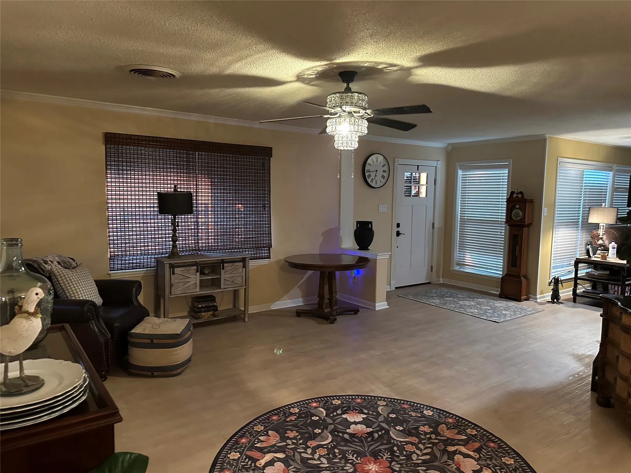 Living area featuring crown molding, a textured ceiling, and a ceiling fan