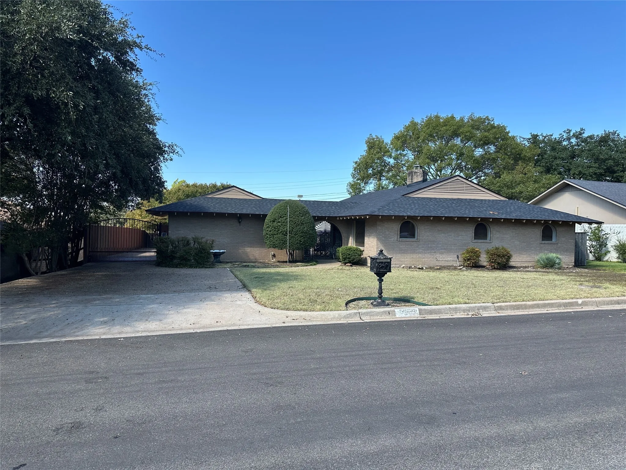 Ranch-style house featuring a front lawn, brick siding, a chimney, and driveway