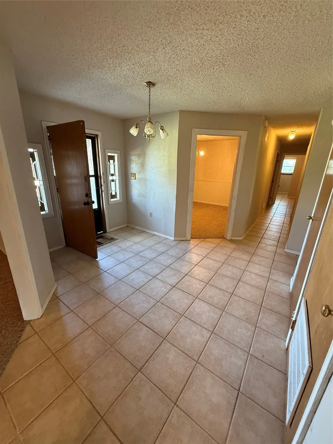 Unfurnished dining area featuring light tile patterned floors, a chandelier, and a textured ceiling