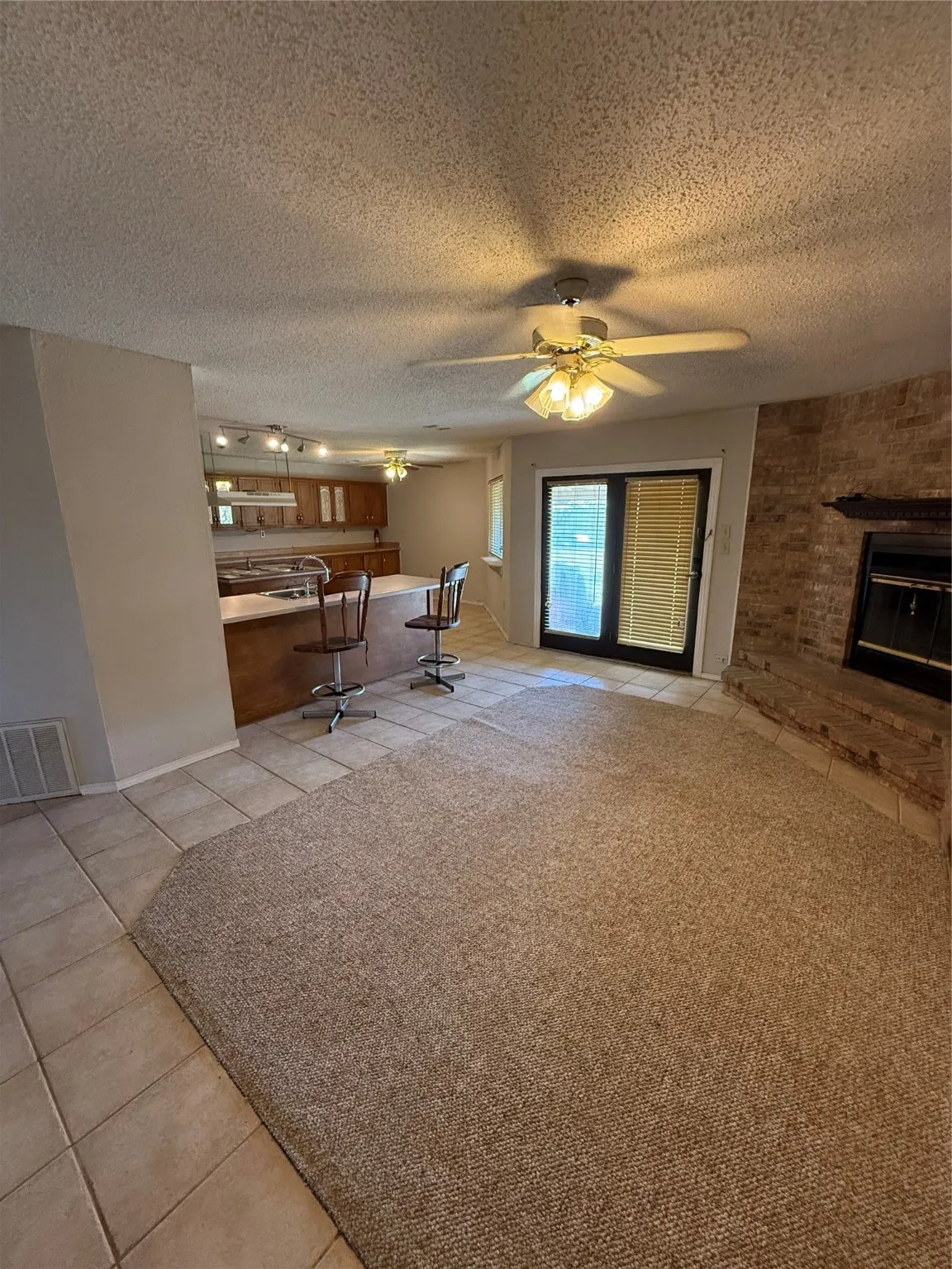 Living room with light tile patterned floors, a textured ceiling, a ceiling fan, and a fireplace