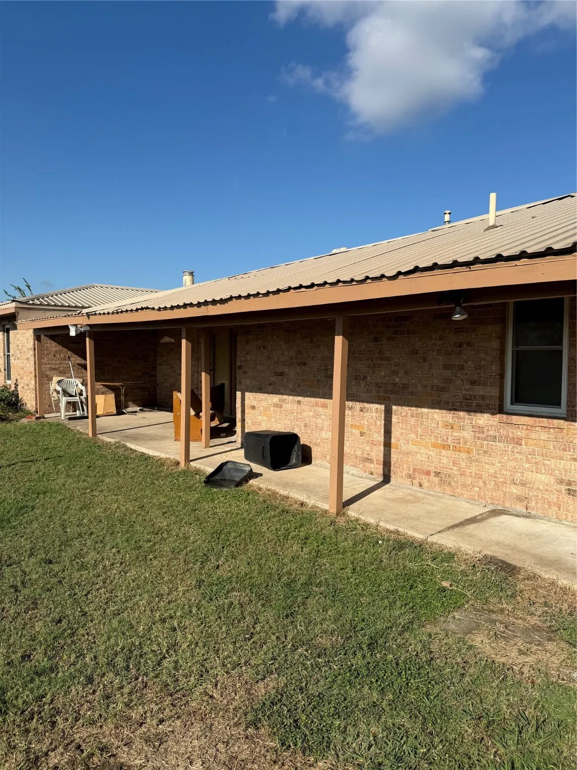 View of property exterior with brick siding, a metal roof, and a lawn