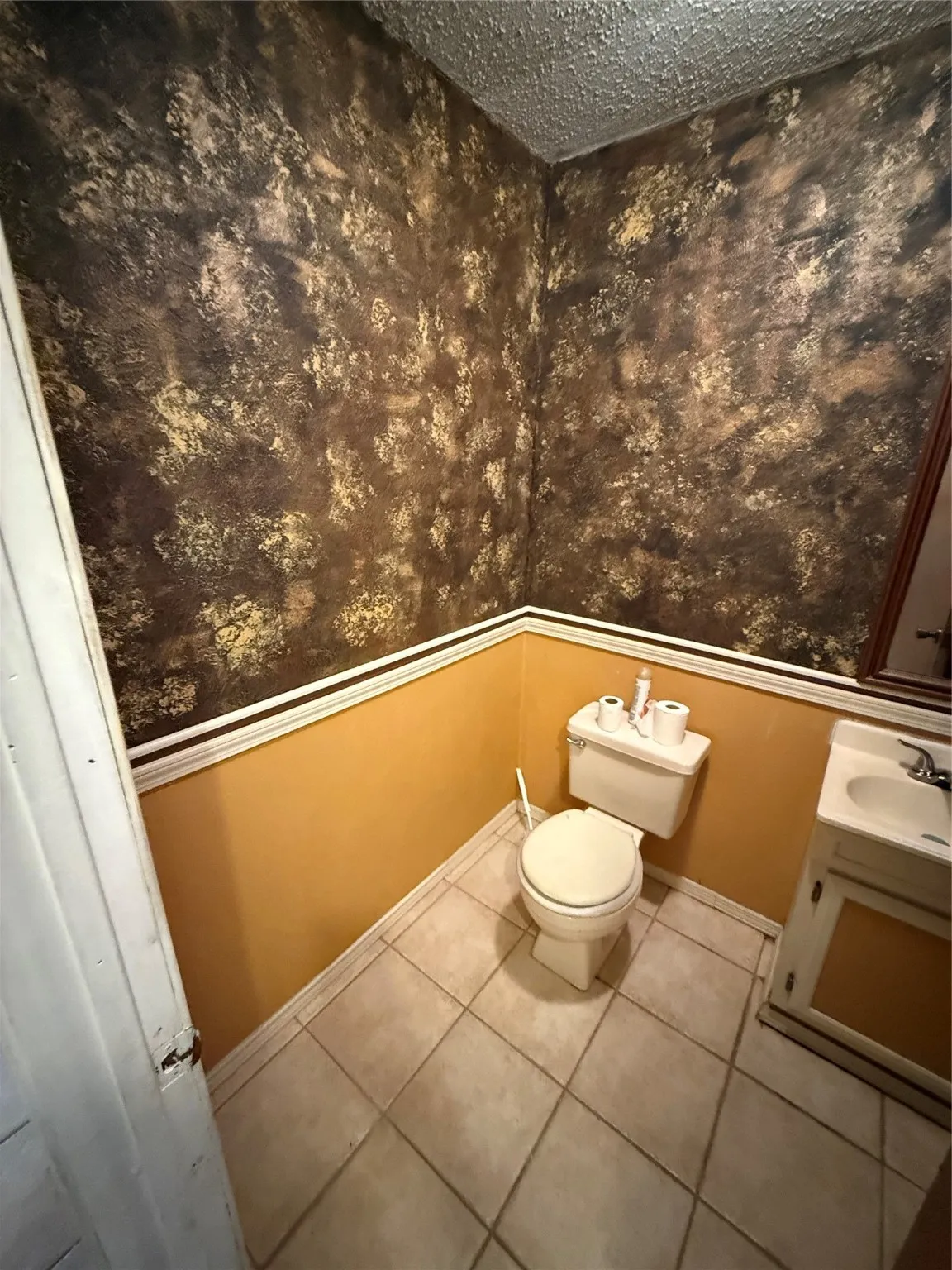 Half bath with tile patterned flooring, vanity, and a textured ceiling