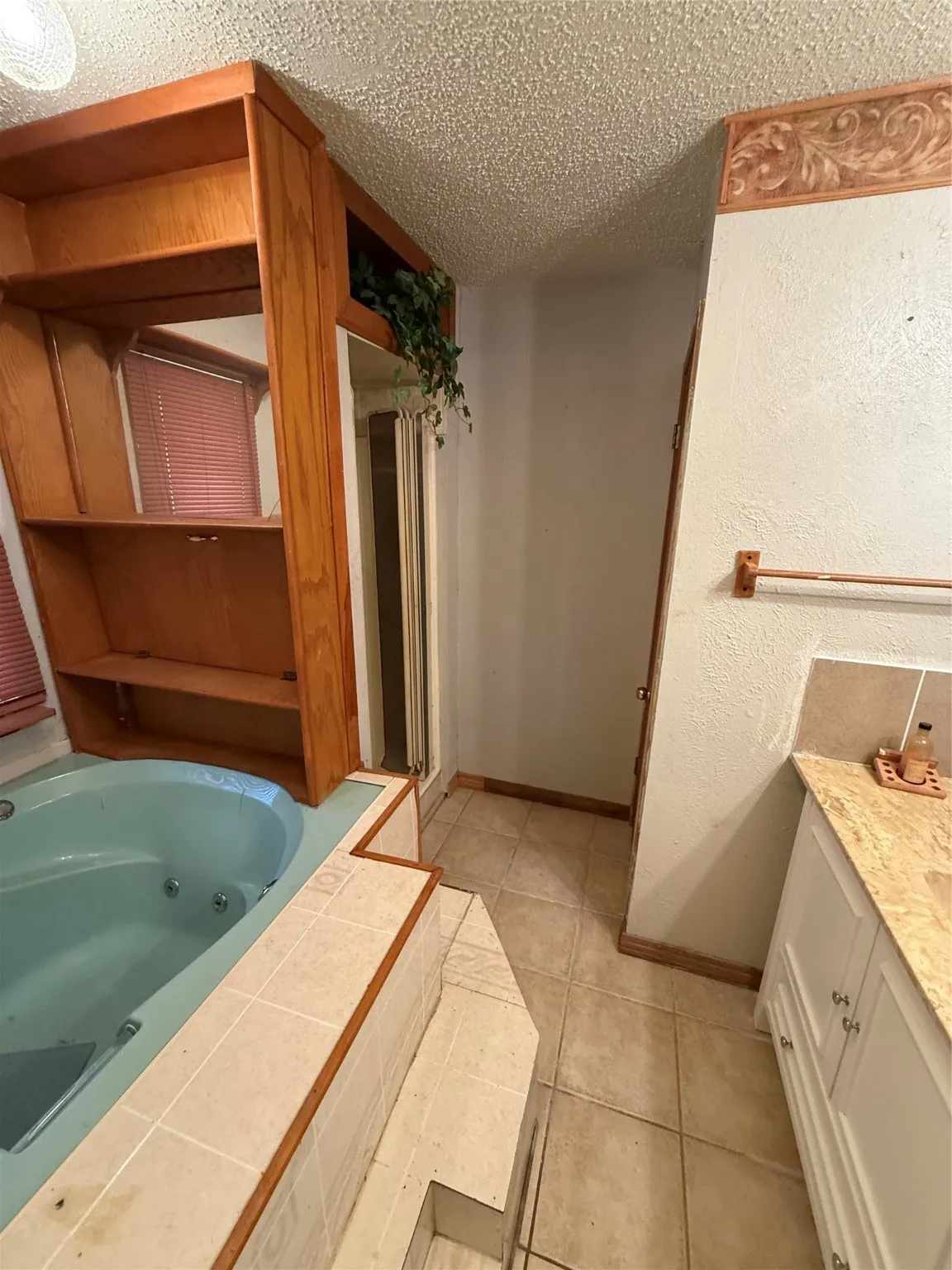 Bathroom featuring vanity, a whirlpool tub, a textured ceiling, a stall shower, and light tile patterned flooring