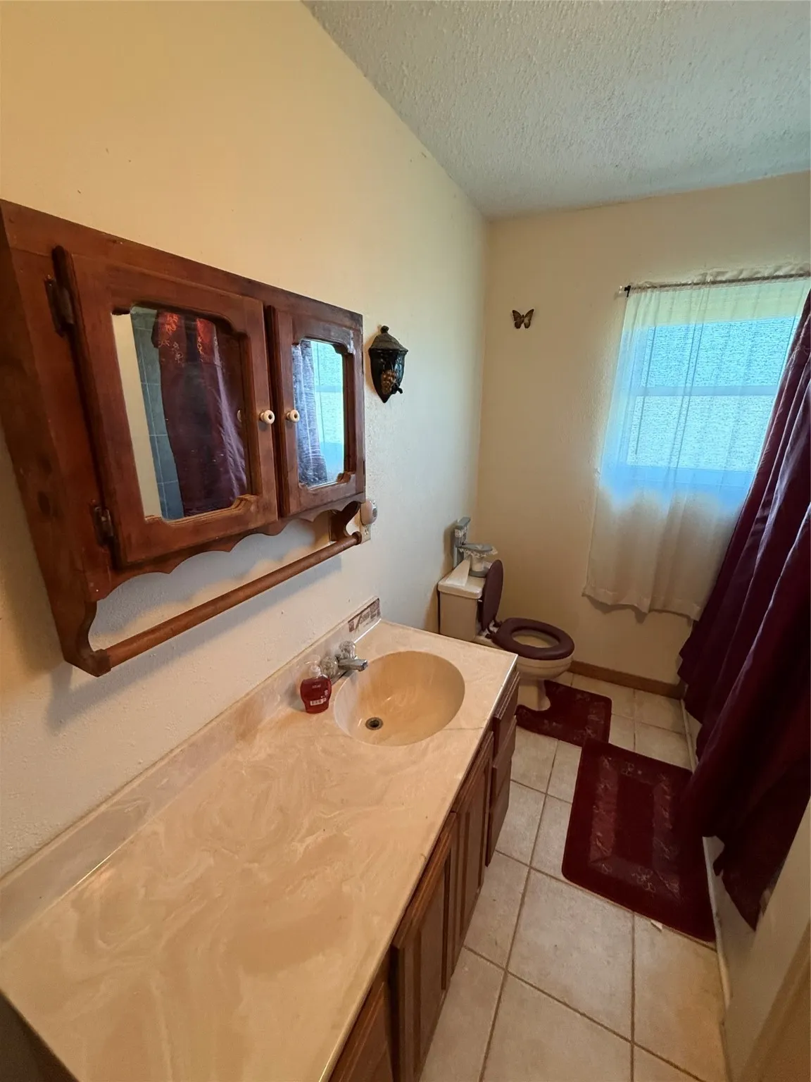 Bathroom with light tile patterned floors, vanity, and a textured ceiling