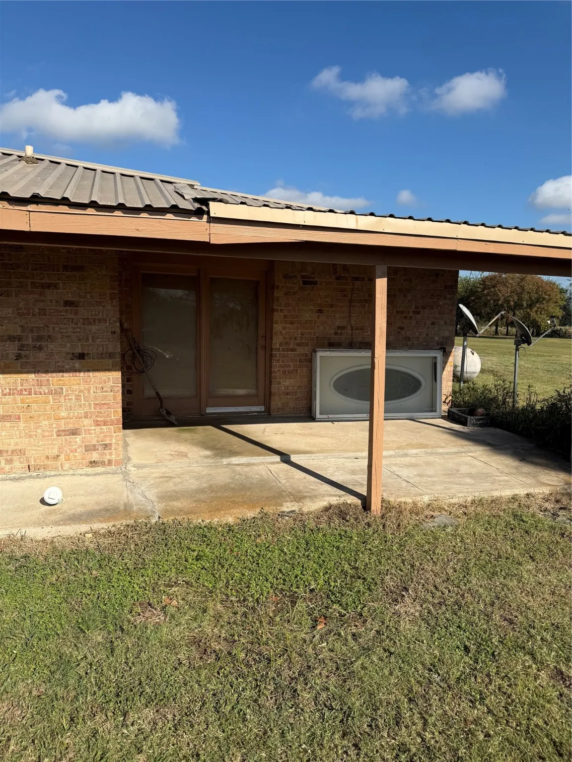 Back of house featuring brick siding, a metal roof, a yard, and a patio area