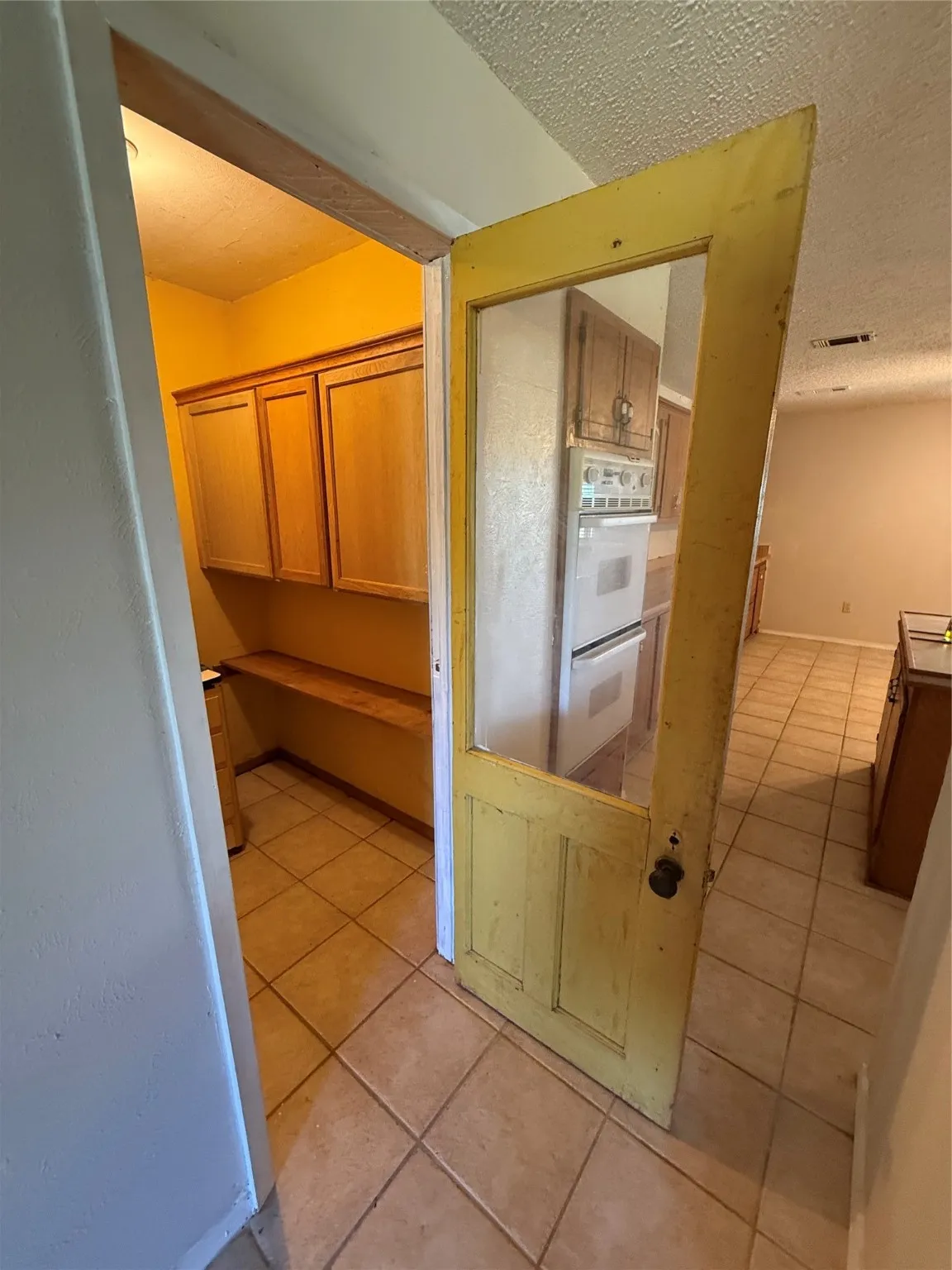 Kitchen featuring a textured ceiling, light tile patterned floors, brown cabinets, and double oven