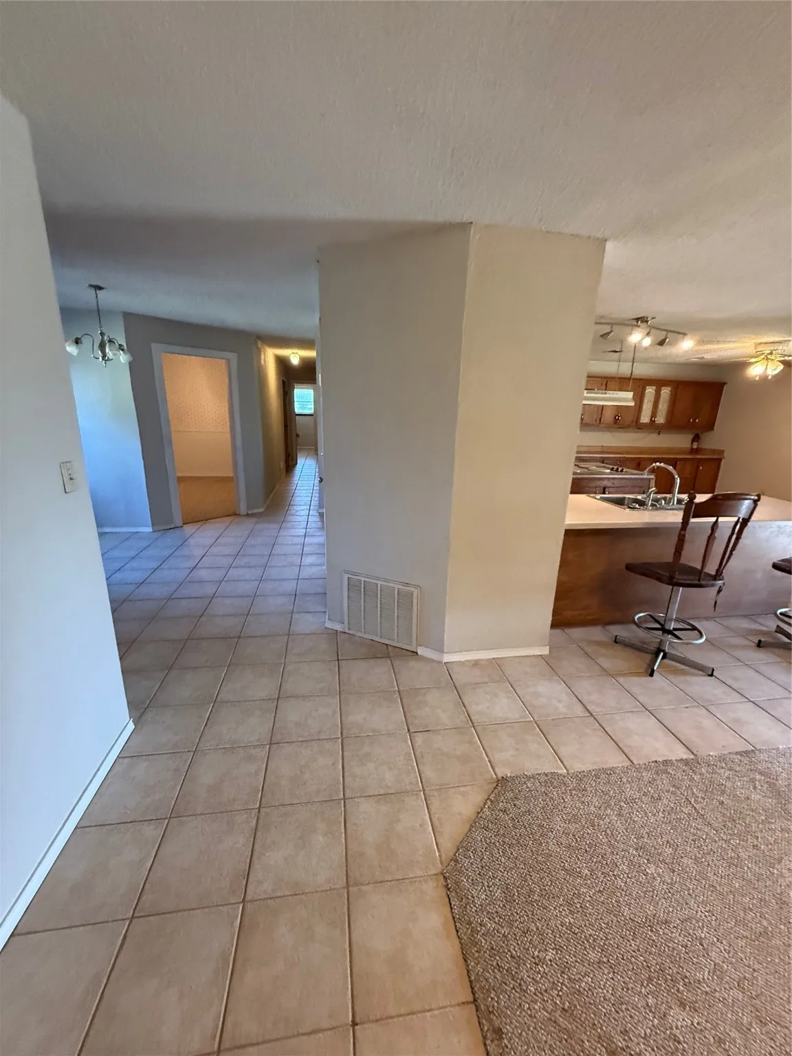 Hallway featuring light tile patterned floors, a textured ceiling, a chandelier, and track lighting