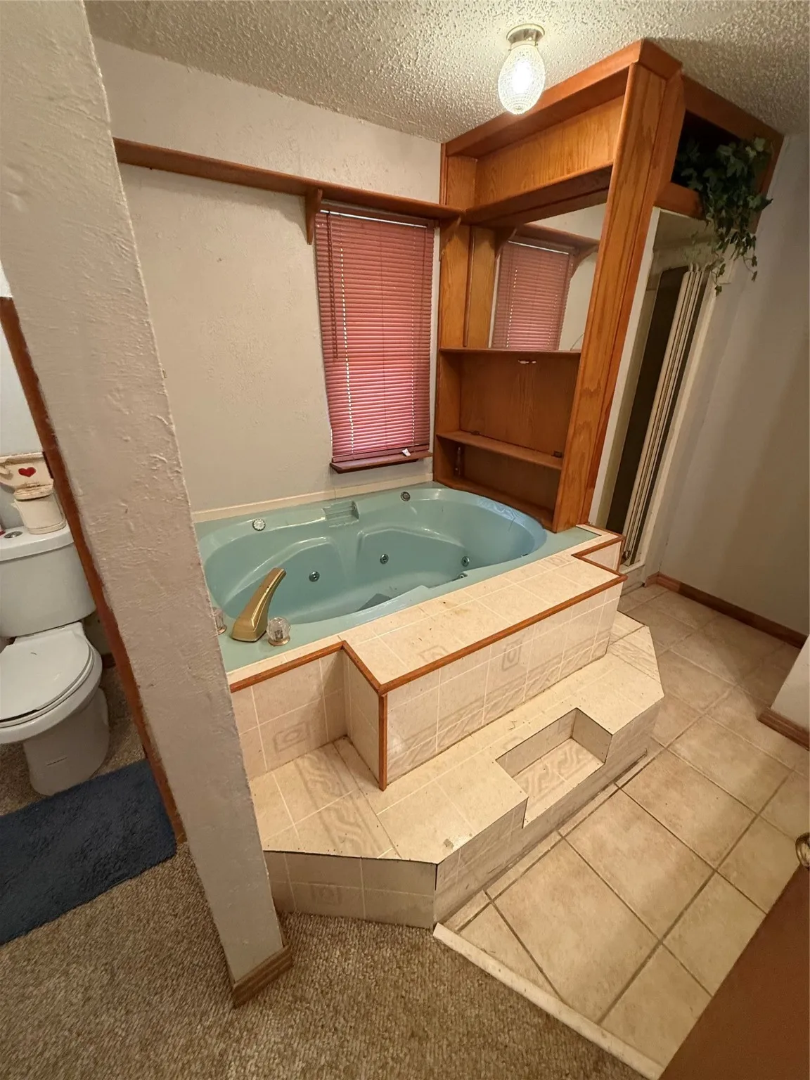 Bathroom featuring a jetted tub, a textured ceiling, a shower stall, a textured wall, and light tile patterned floors
