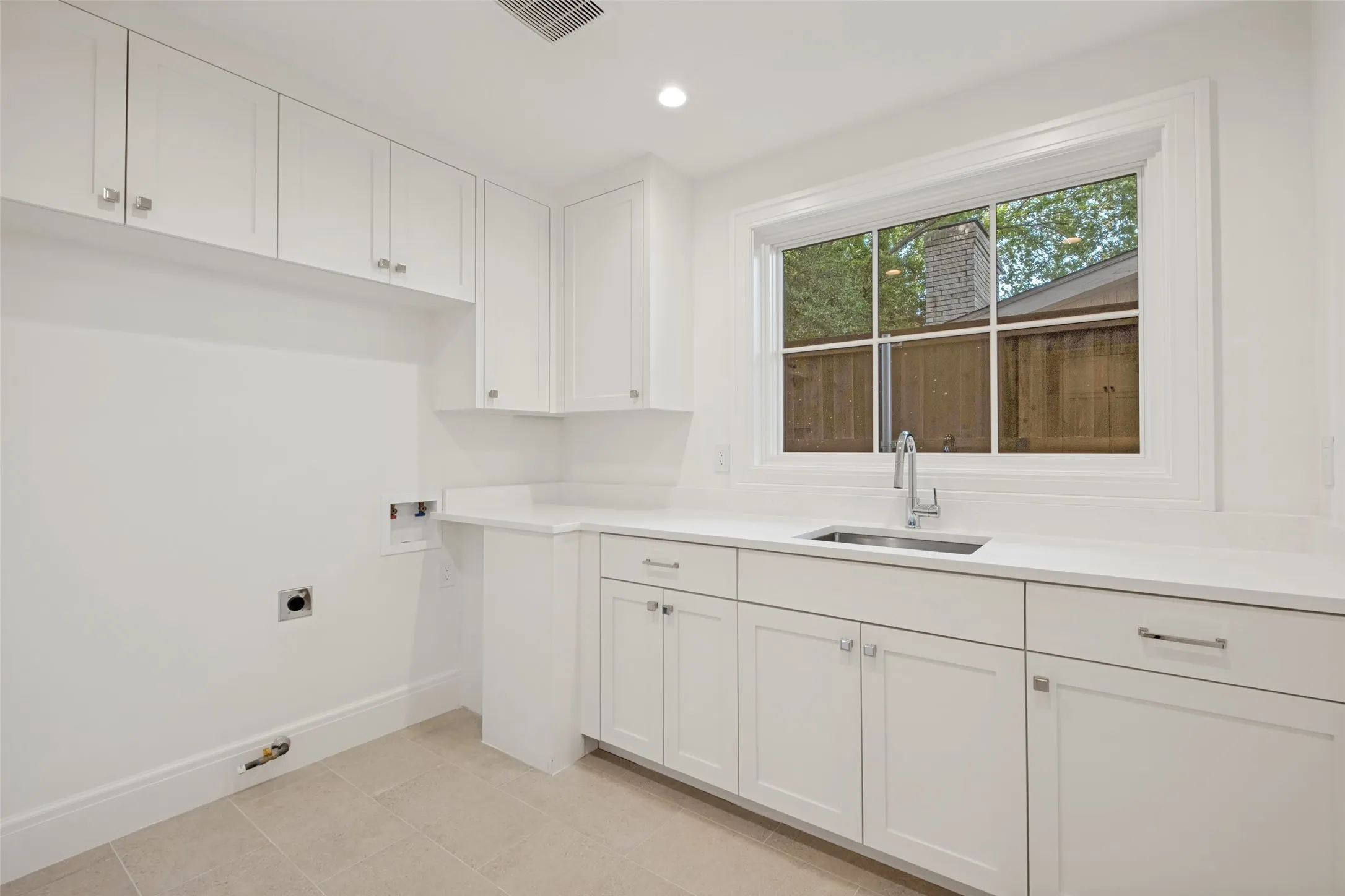 Spacious first-floor laundry room featuring a utility sink and abundant storage space.
